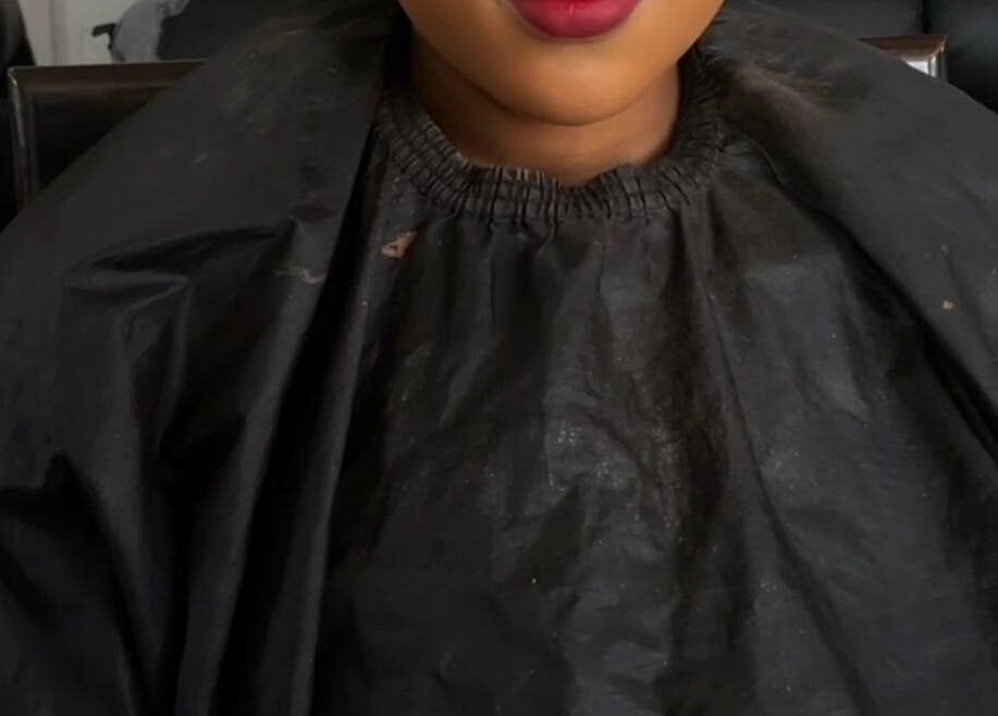 Focused shot of client in black cape at Beats By Sange, Cape Town, Western Cape, ZA, showcasing beauty preparation.