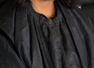 Client at Beats By Sange in Cape Town, Western Cape, ZA, wearing a black salon gown for a beauty treatment.