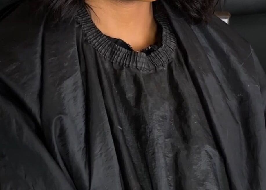 Client at Beats By Sange in Cape Town, Western Cape, ZA, wearing a black salon gown for a beauty treatment.