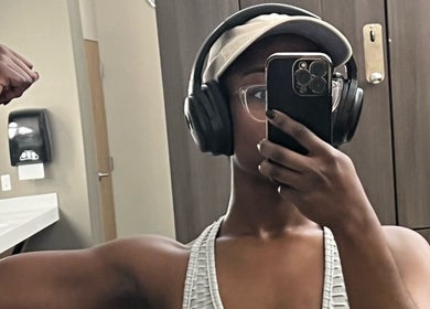 Person flexing muscles in gym at Fit Mom Coaching, Wyncote, Pennsylvania, US, wearing headphones.