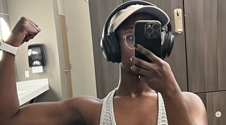 Person flexing muscles in gym at Fit Mom Coaching, Wyncote, Pennsylvania, US, wearing headphones.