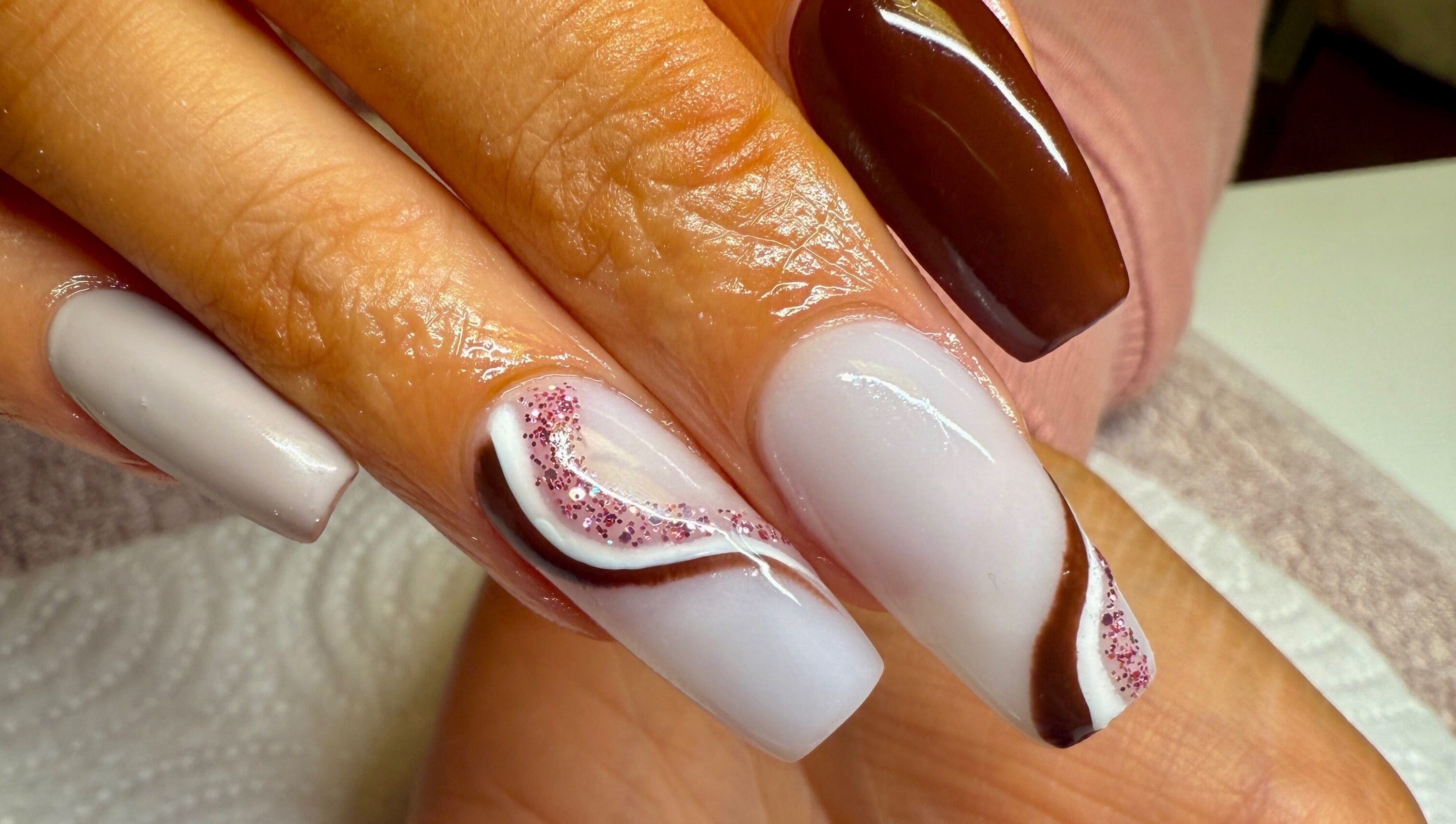 Stylish nail art at pnail_studio, Balbriggan, County Dublin, IE showcasing brown and white design with glitter.