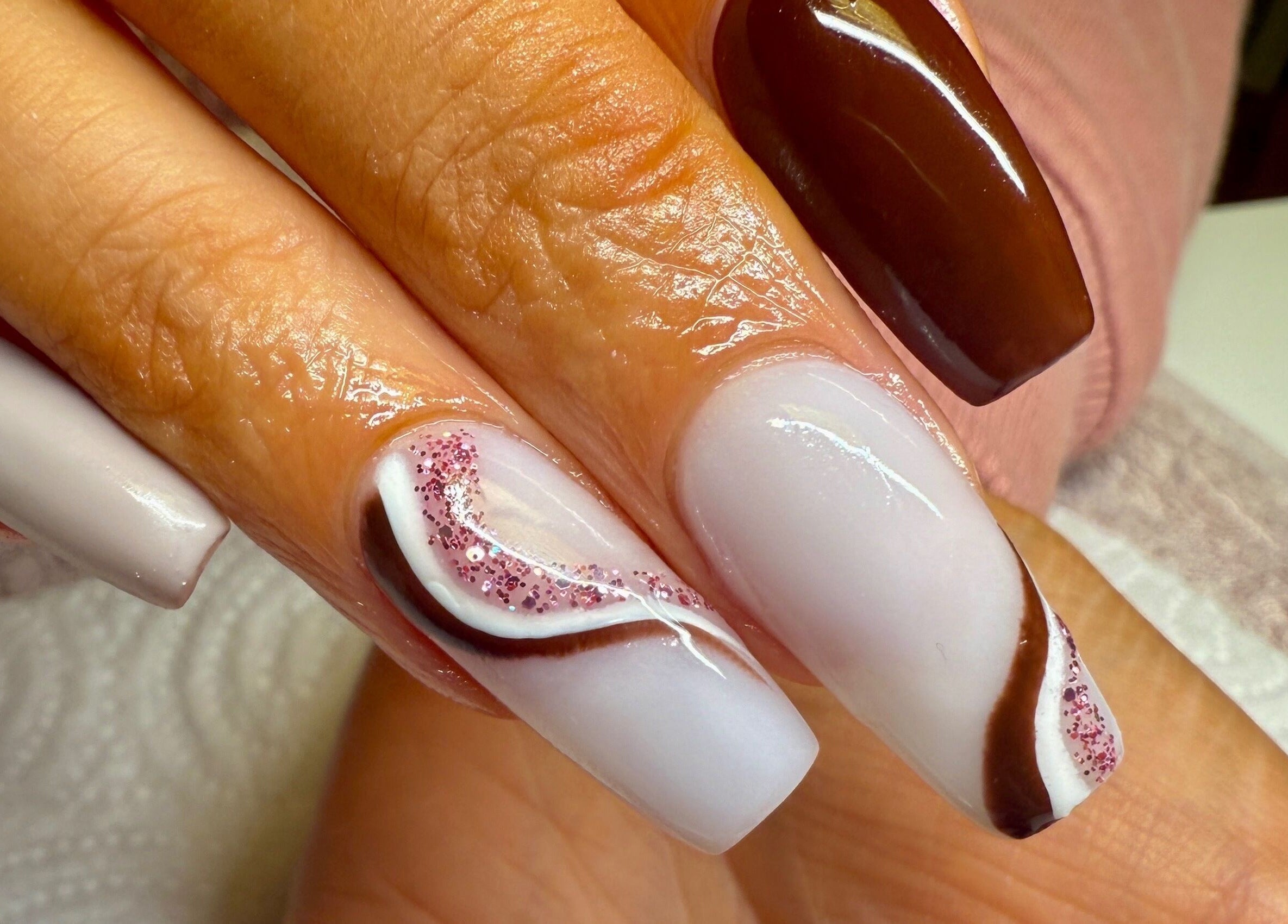 Stylish nail art at pnail_studio, Balbriggan, County Dublin, IE showcasing brown and white design with glitter.