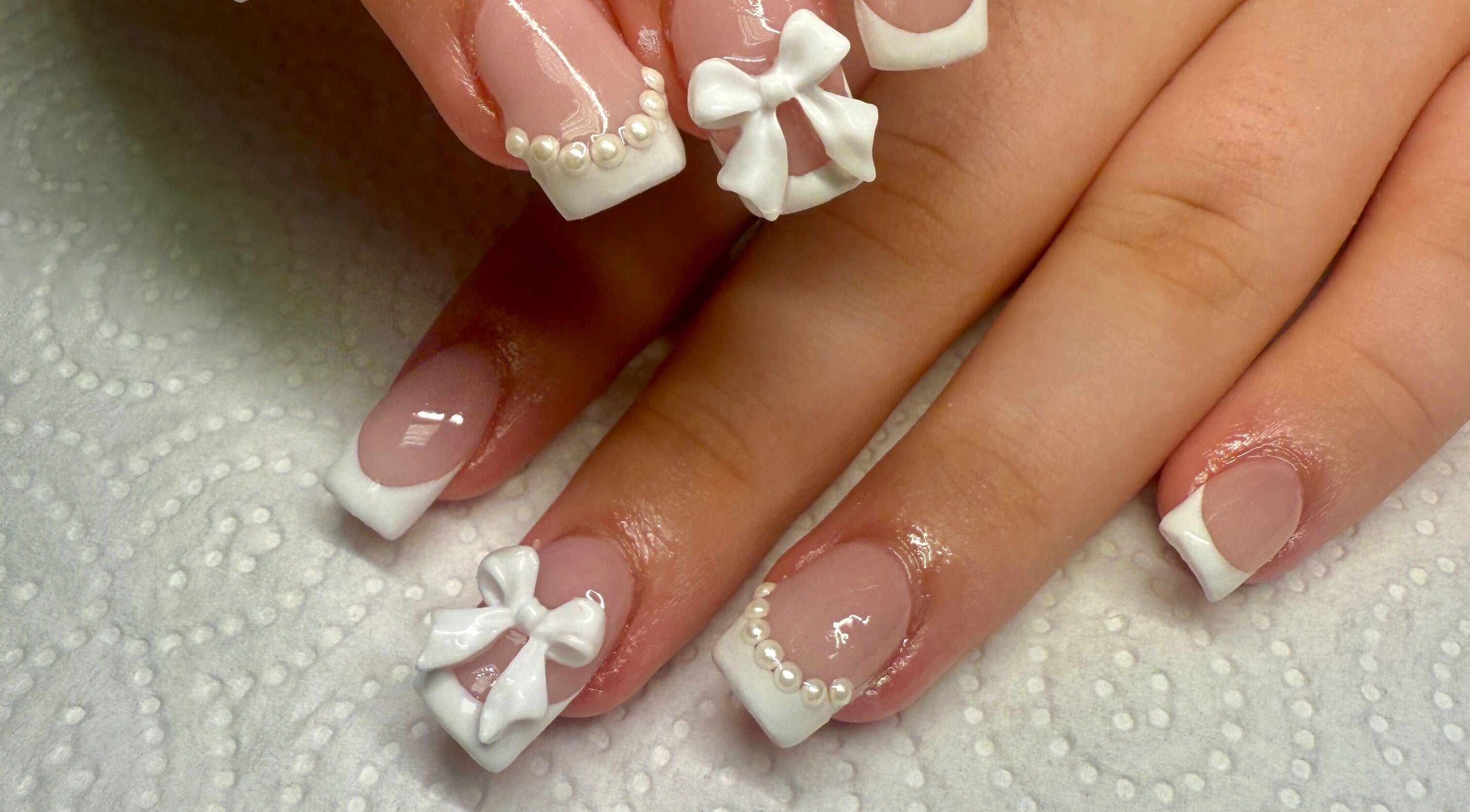 Elegant French tip nails with bows at pnail_studio, Balbriggan, County Dublin, IE.