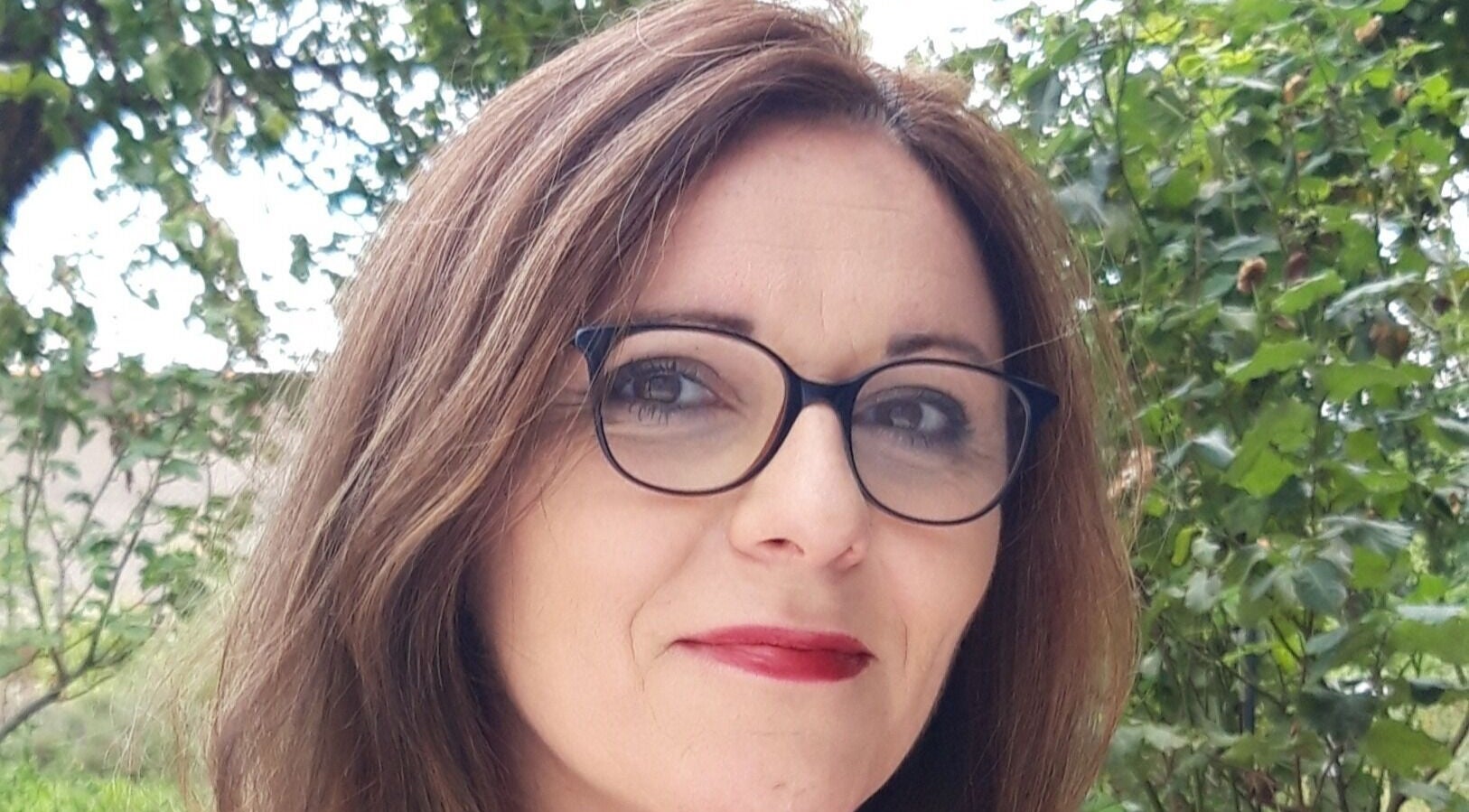 Portrait d'une femme souriante à Christ'ailes, Romagnat, Auvergne-rhône-alpes, FR, entourée de verdure.