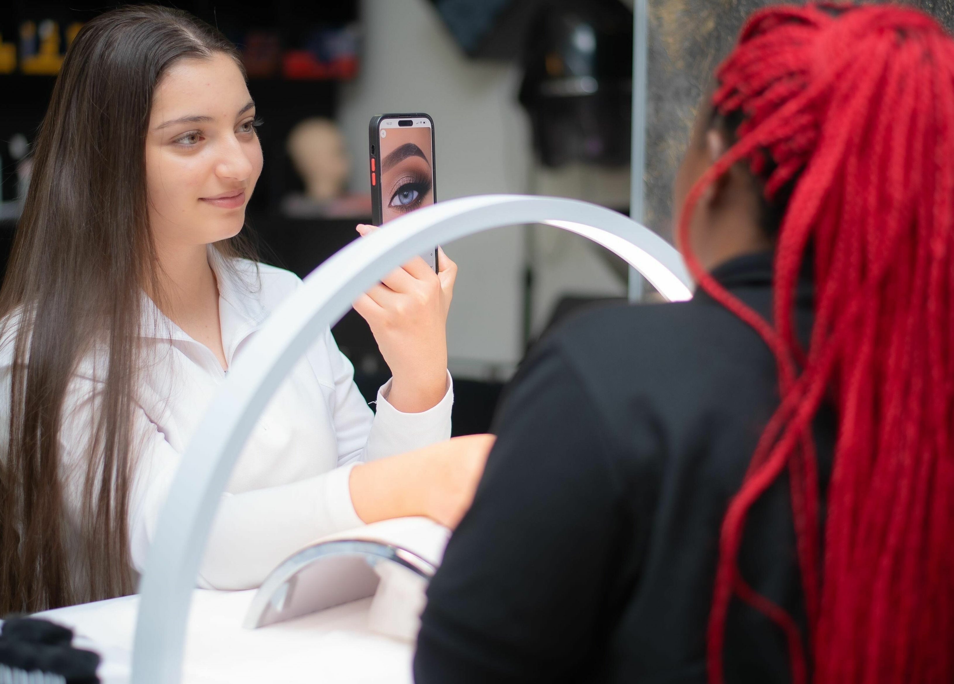 Client views eye makeup at Mkh Beauty House, Johannesburg, Gauteng, ZA, consulting with stylist.