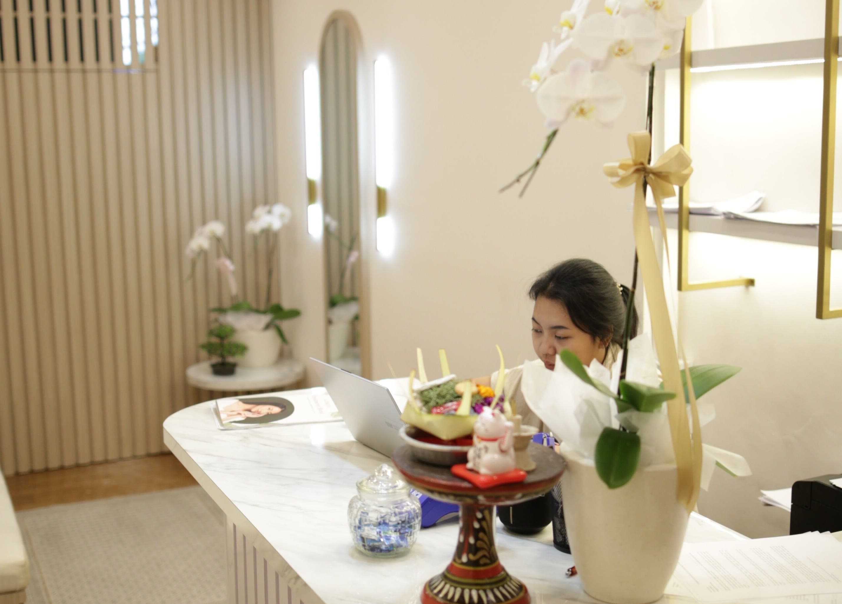 Reception desk at LENORA BEAUTY STUDIO, Bali, ID. Elegant decor with orchids and welcoming ambiance.