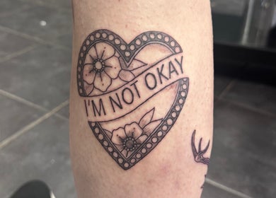 Heart-shaped 'I'm not okay' tattoo with flowers at Asatru Tattoos, Cardiff, Wales, GB.