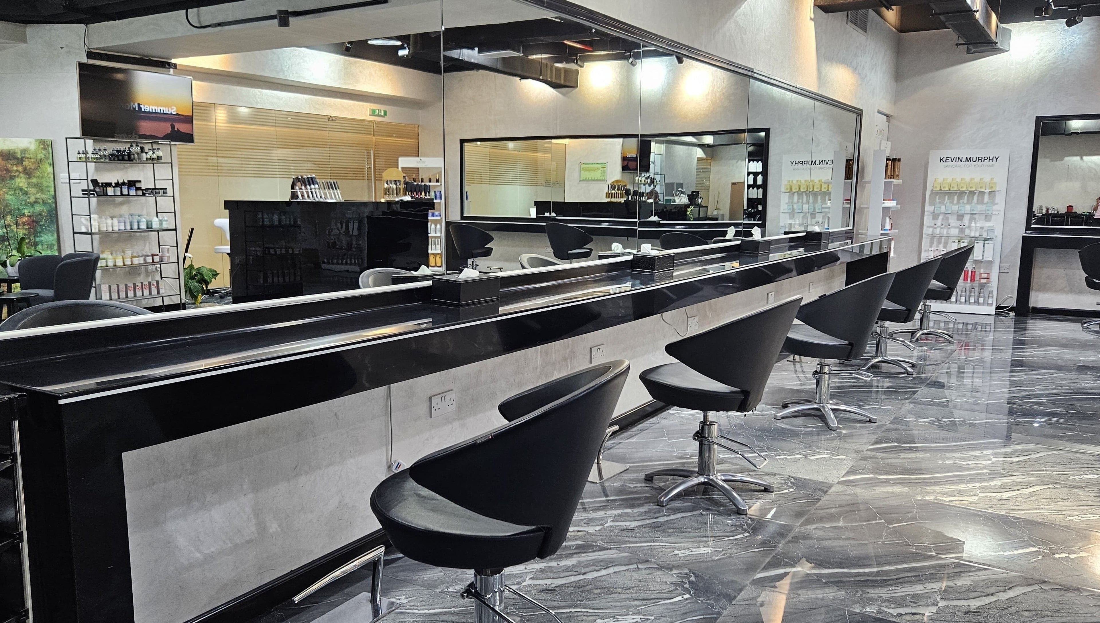 Modern interior of Flair Beauty Salon in Abu Dhabi, AE, featuring sleek black salon chairs and mirrored walls.