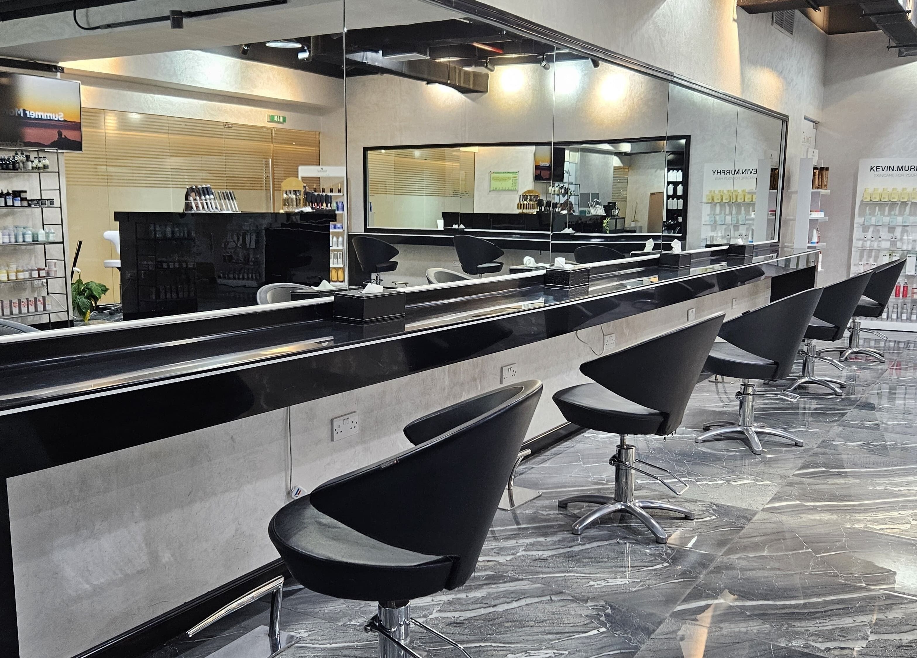 Modern interior of Flair Beauty Salon in Abu Dhabi, AE, featuring sleek black salon chairs and mirrored walls.