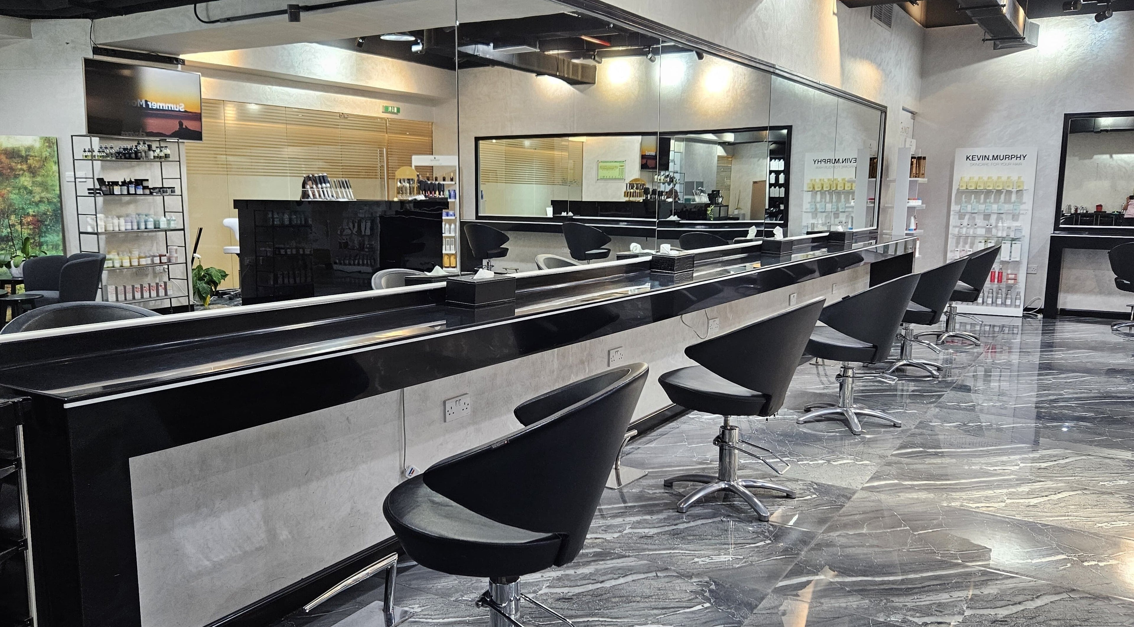 Modern interior of Flair Beauty Salon in Abu Dhabi, AE, featuring sleek black salon chairs and mirrored walls.