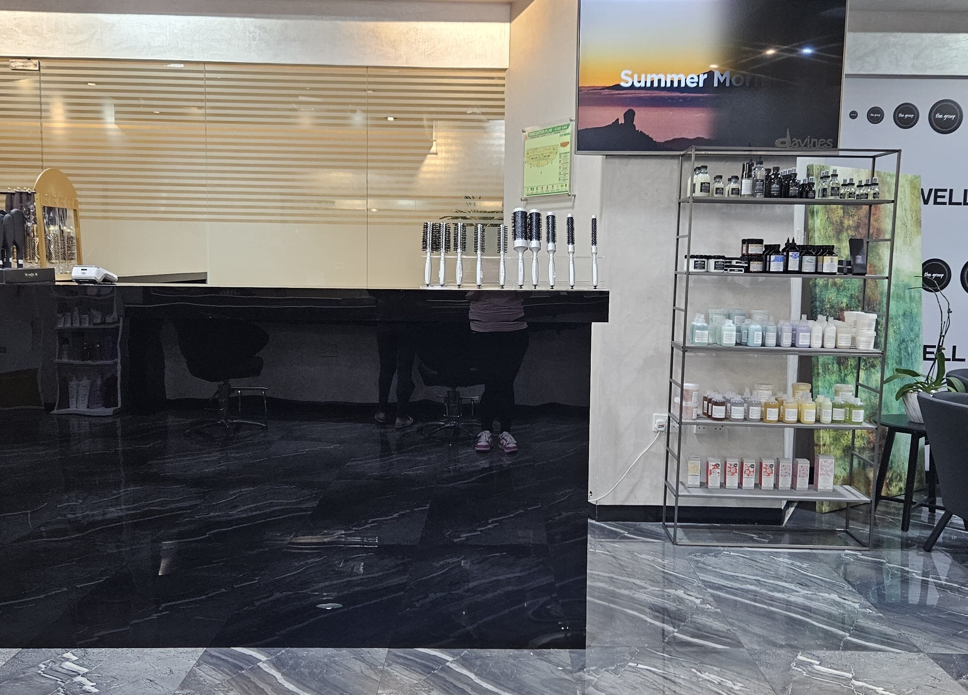 Reception area of Flair Beauty Salon in Abu Dhabi, featuring a sleek black counter and display shelves.