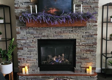 Inviting stone fireplace at The Bodhi Tree, Lancaster, New York, US with candles and greenery.