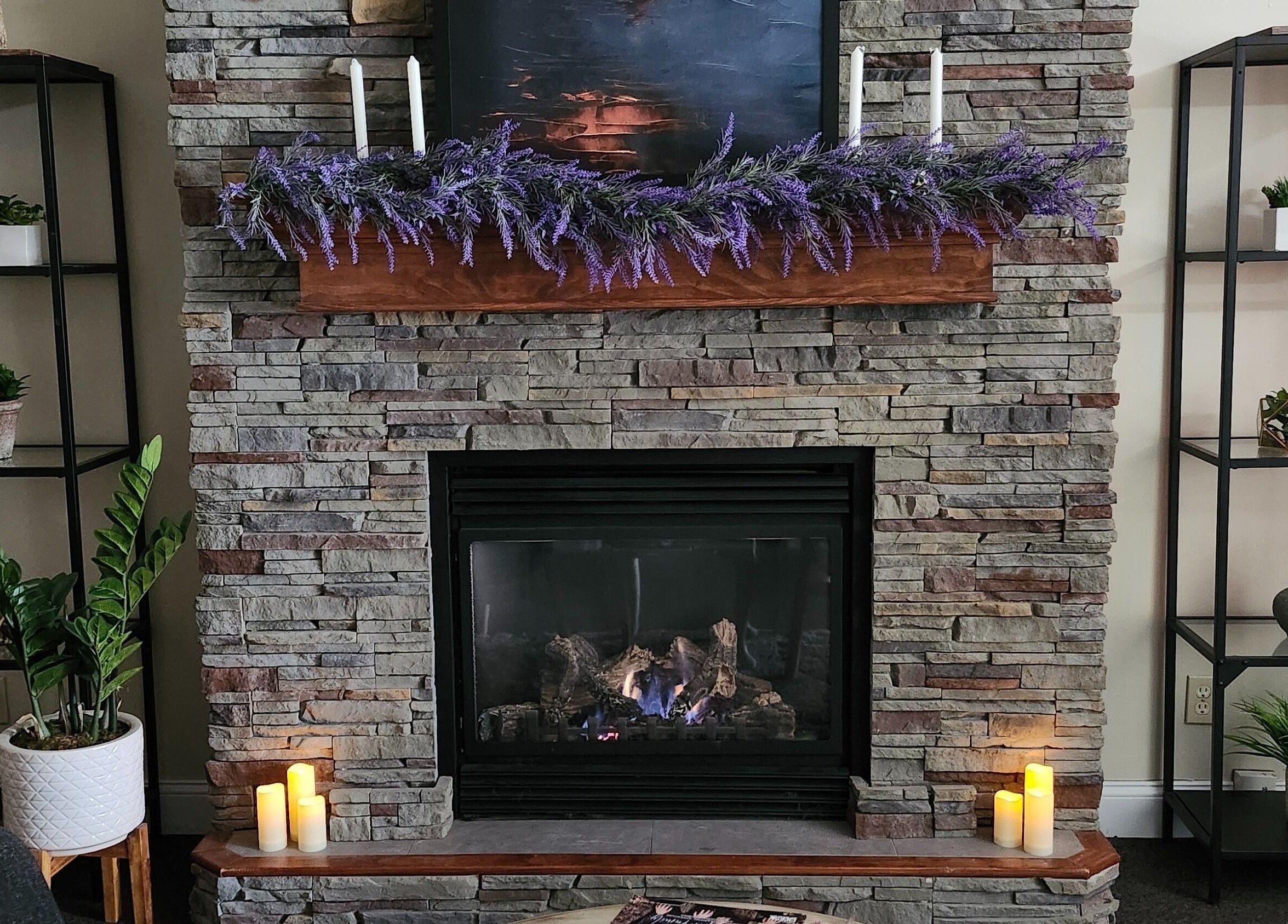 Inviting stone fireplace at The Bodhi Tree, Lancaster, New York, US with candles and greenery.