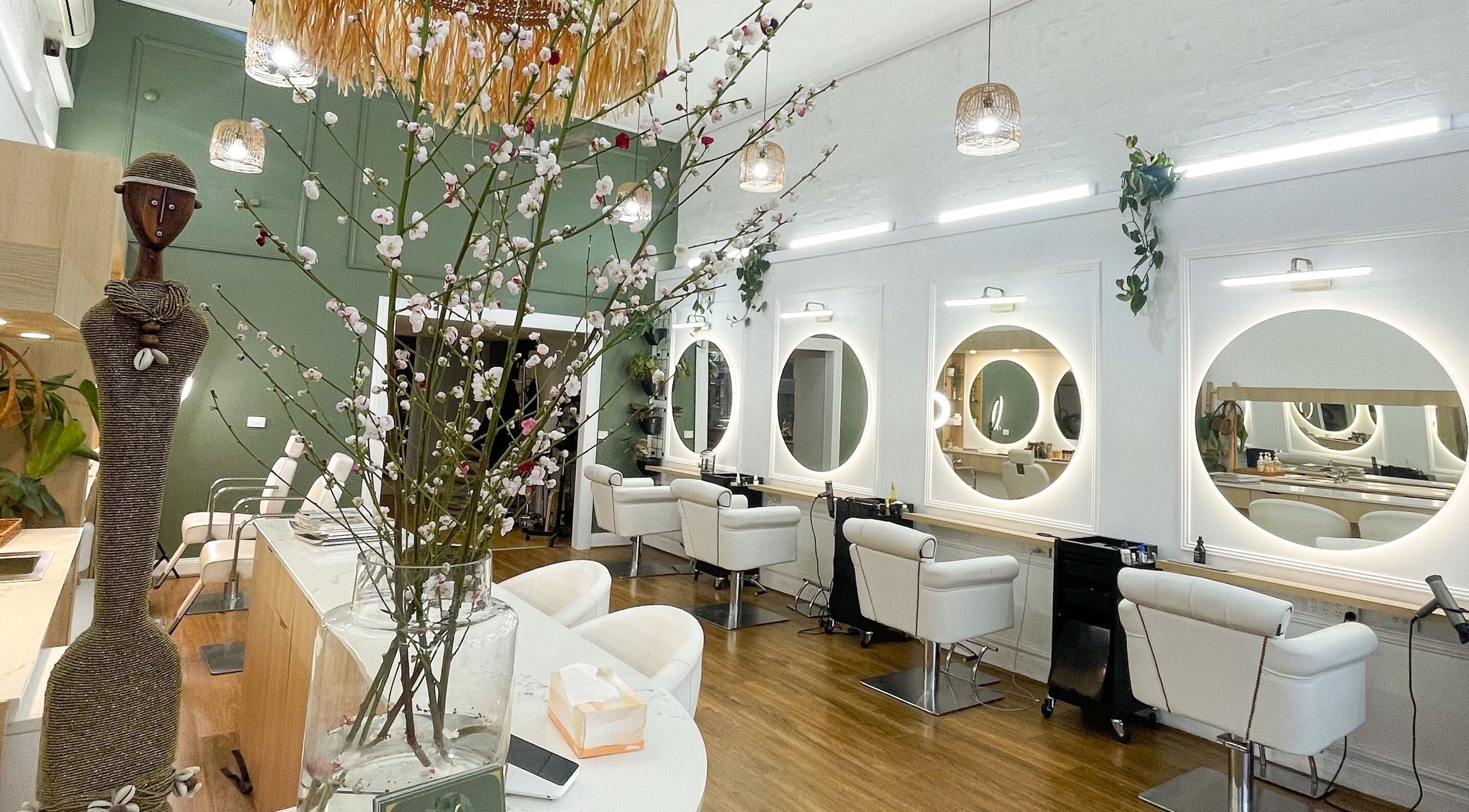 Interior sofisticado do Mv Hair Spa em Melbourne, Victoria, AU, com espelhos iluminados e cadeiras elegantes.