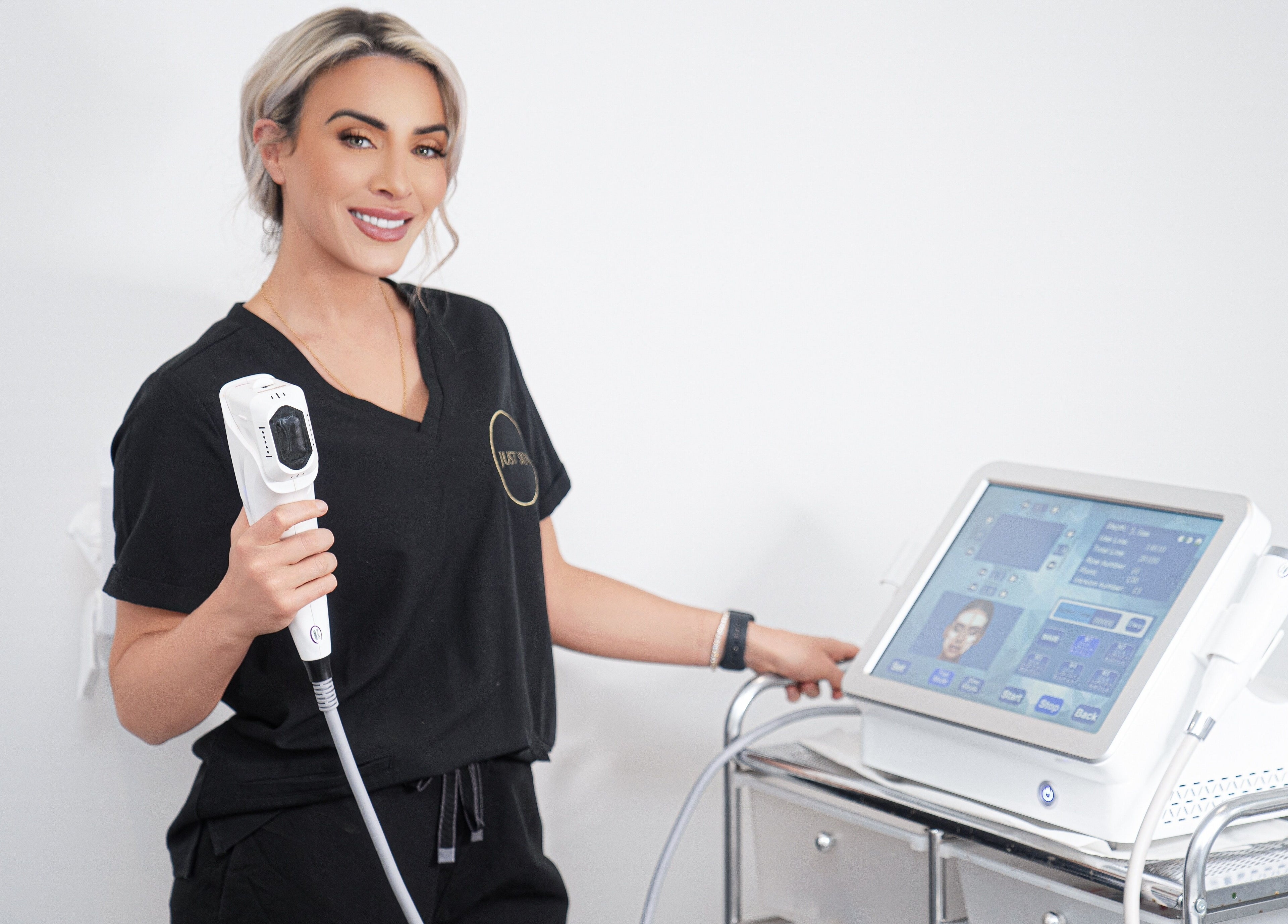 Treatment specialist at Just Skin Uk, Cardiff, Wales, GB, holding aesthetic device smiling confidently.