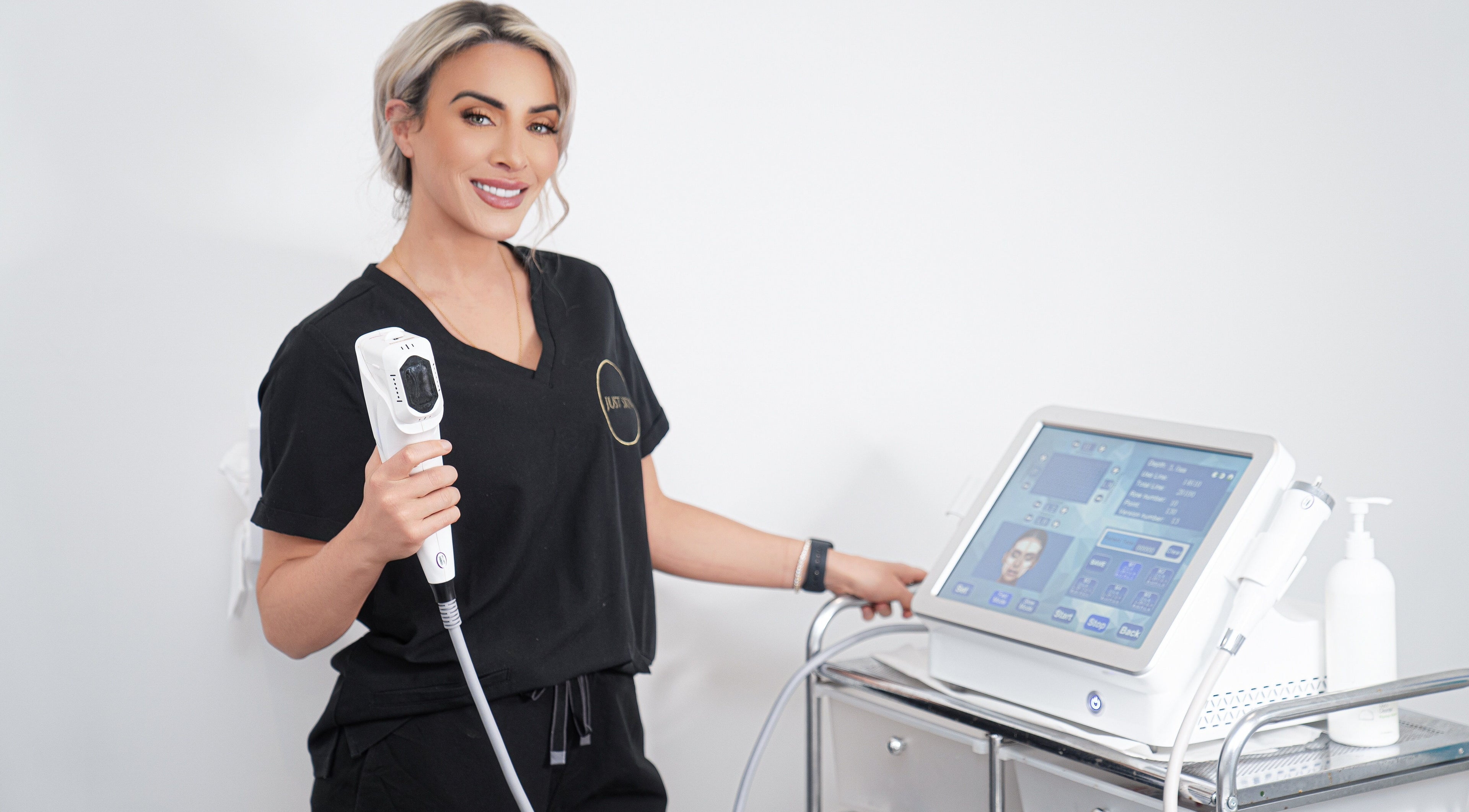 Treatment specialist at Just Skin Uk, Cardiff, Wales, GB, holding aesthetic device smiling confidently.