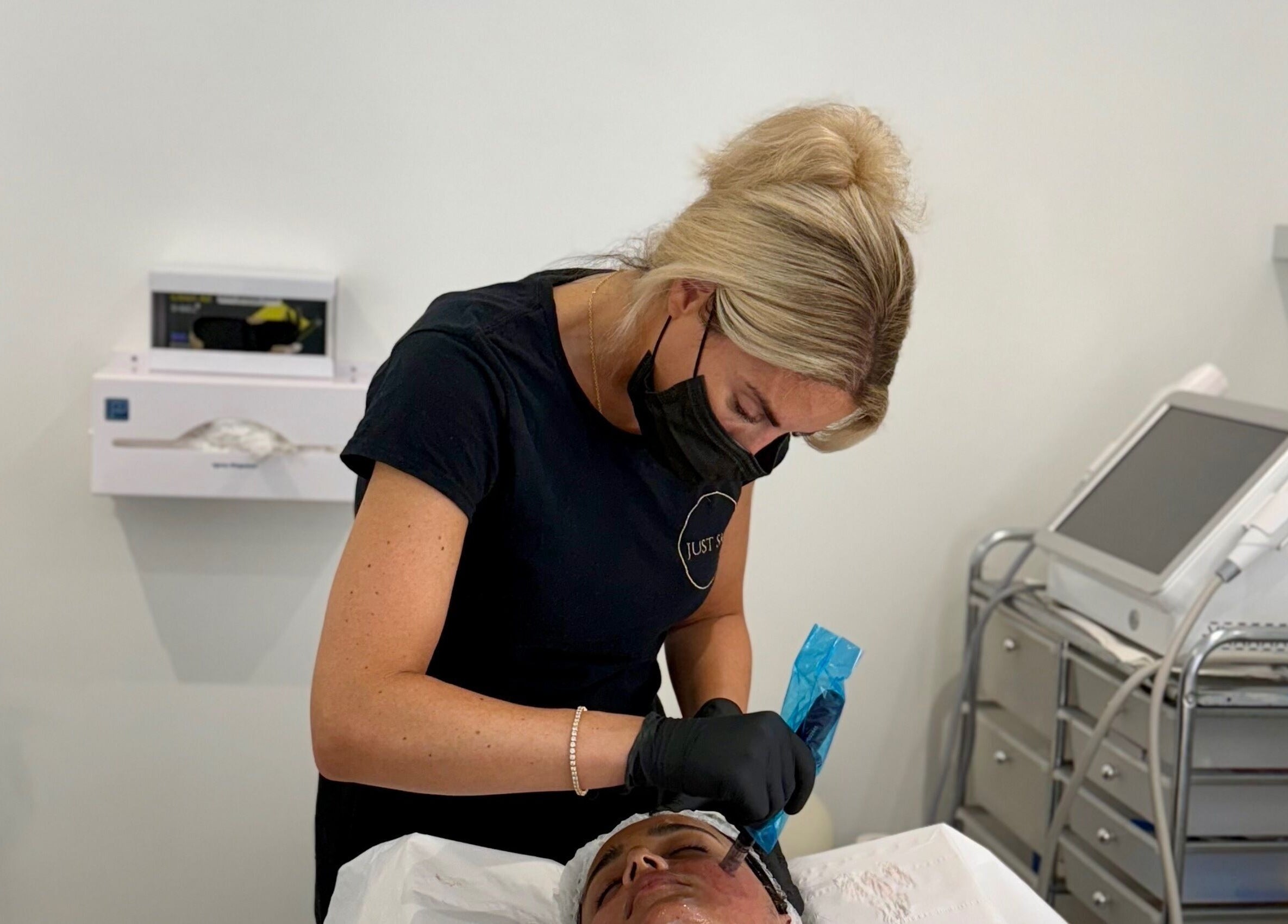 Skincare professional at Just Skin Uk in Cardiff, Wales, GB performing a facial treatment in a modern clinic.