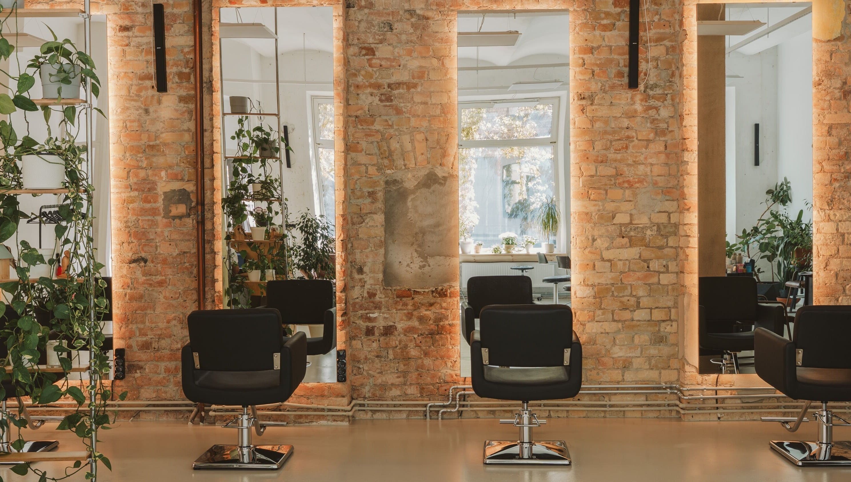Cozy salon at Grieze, Rīga, LV, featuring modern chairs, mirrors, and lush plants.