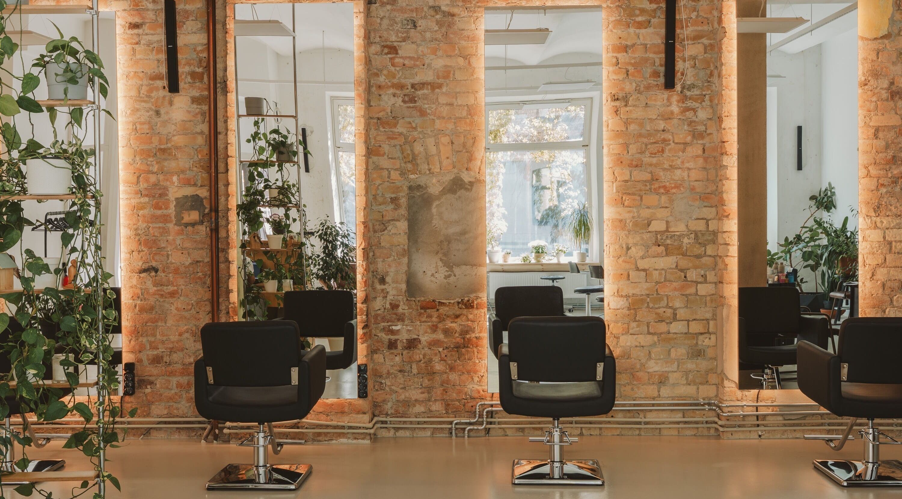 Cozy salon at Grieze, Rīga, LV, featuring modern chairs, mirrors, and lush plants.