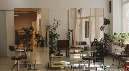 Modern salon interior at Grieze, Rīga, LV, with stylish chairs, mirrors, and greenery.