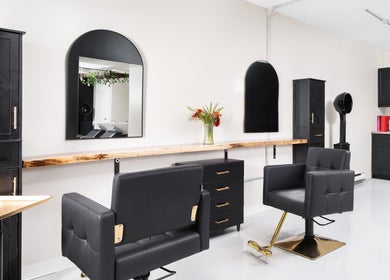 Chic interior of Rustic Roots Hair Lounge, Thorold, Ontario, CA, featuring modern salon chairs and sleek cabinetry.