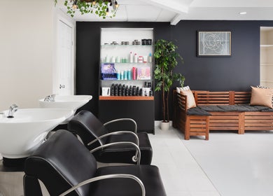 Chic interior of Rustic Roots Hair Lounge in Thorold, Ontario, CA, featuring modern black chairs and wooden decor.