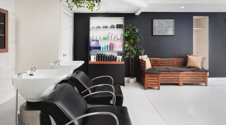 Chic interior of Rustic Roots Hair Lounge in Thorold, Ontario, CA, featuring modern black chairs and wooden decor.