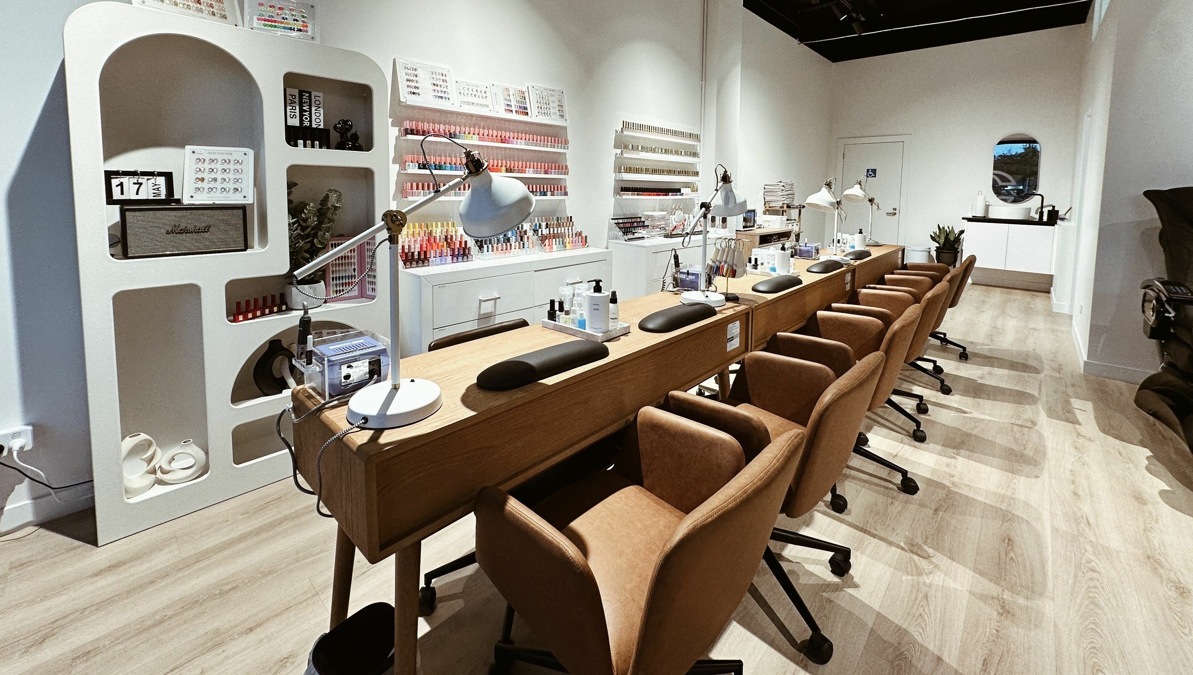 Modern nail salon at Cosmo Nails & Beauty, Auckland, featuring sleek manicure stations and polish wall display.