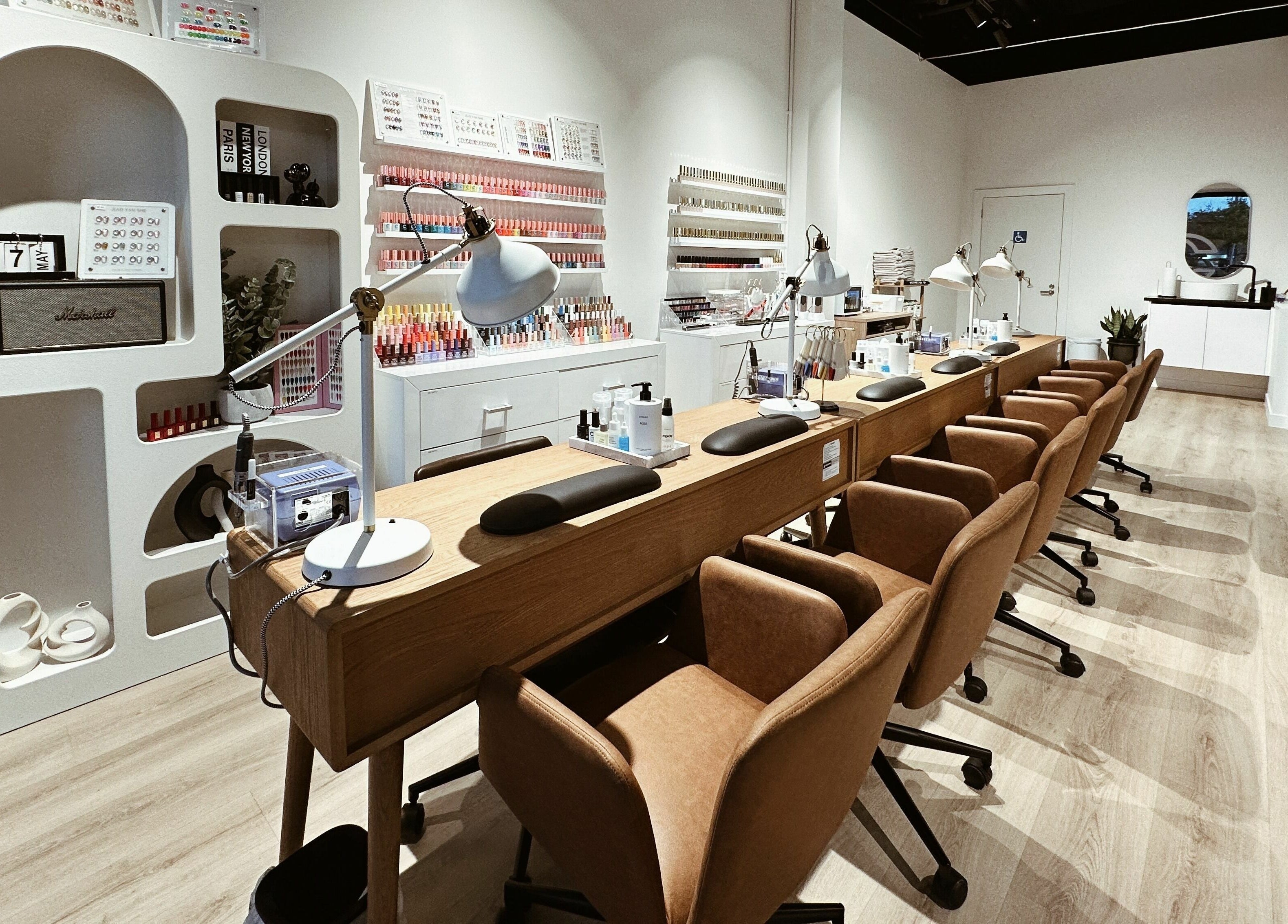 Modern nail salon at Cosmo Nails & Beauty, Auckland, featuring sleek manicure stations and polish wall display.