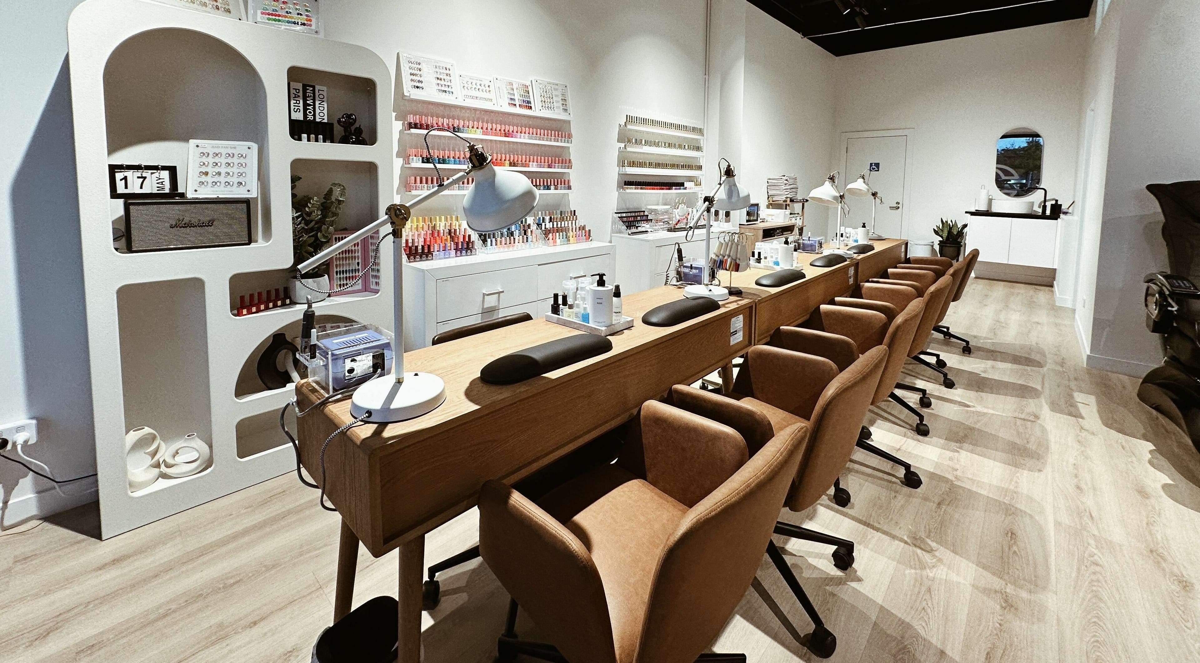 Modern nail salon at Cosmo Nails & Beauty, Auckland, featuring sleek manicure stations and polish wall display.