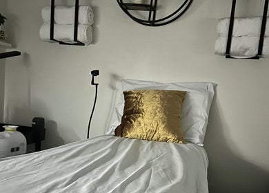 Serene treatment room at Modest Skin, San Diego, California, US with plush bed and golden decor.