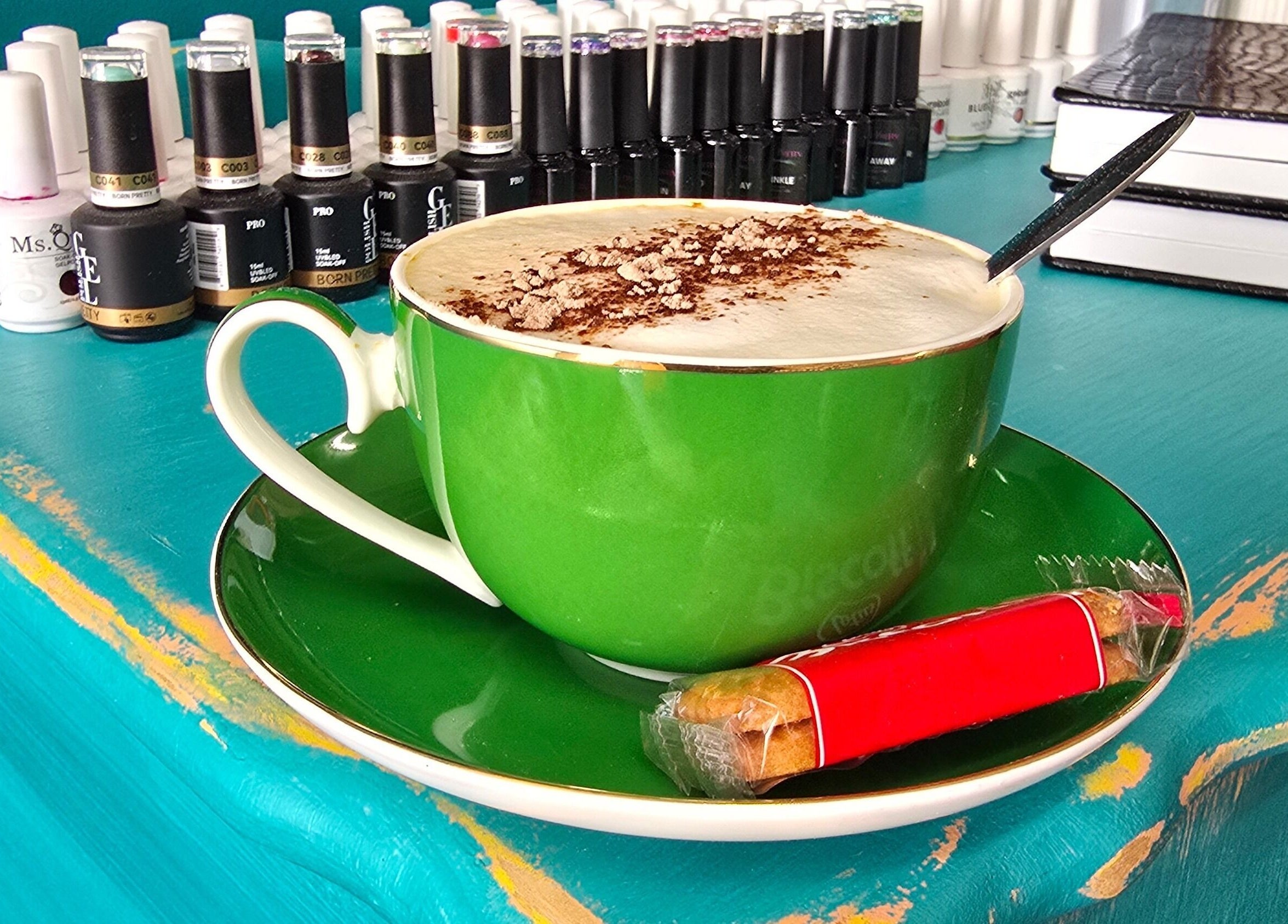 Green cup of coffee at Treat Yourself Beautifully, Clermont, Queensland, AU with nail polish display.
