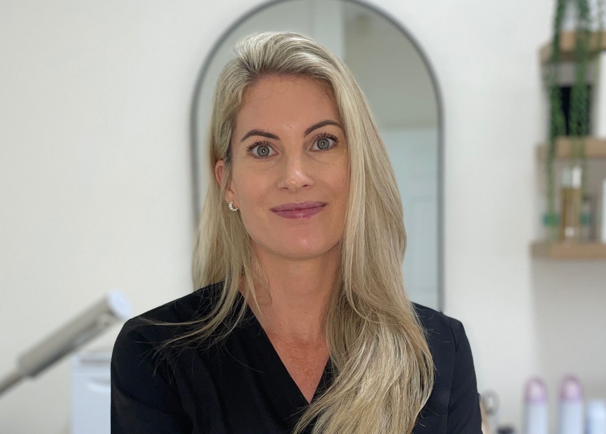 Professional woman in Studio XO La Lucia, Durban North, Kwazulu-natal, ZA, smiling in a serene skincare setting.