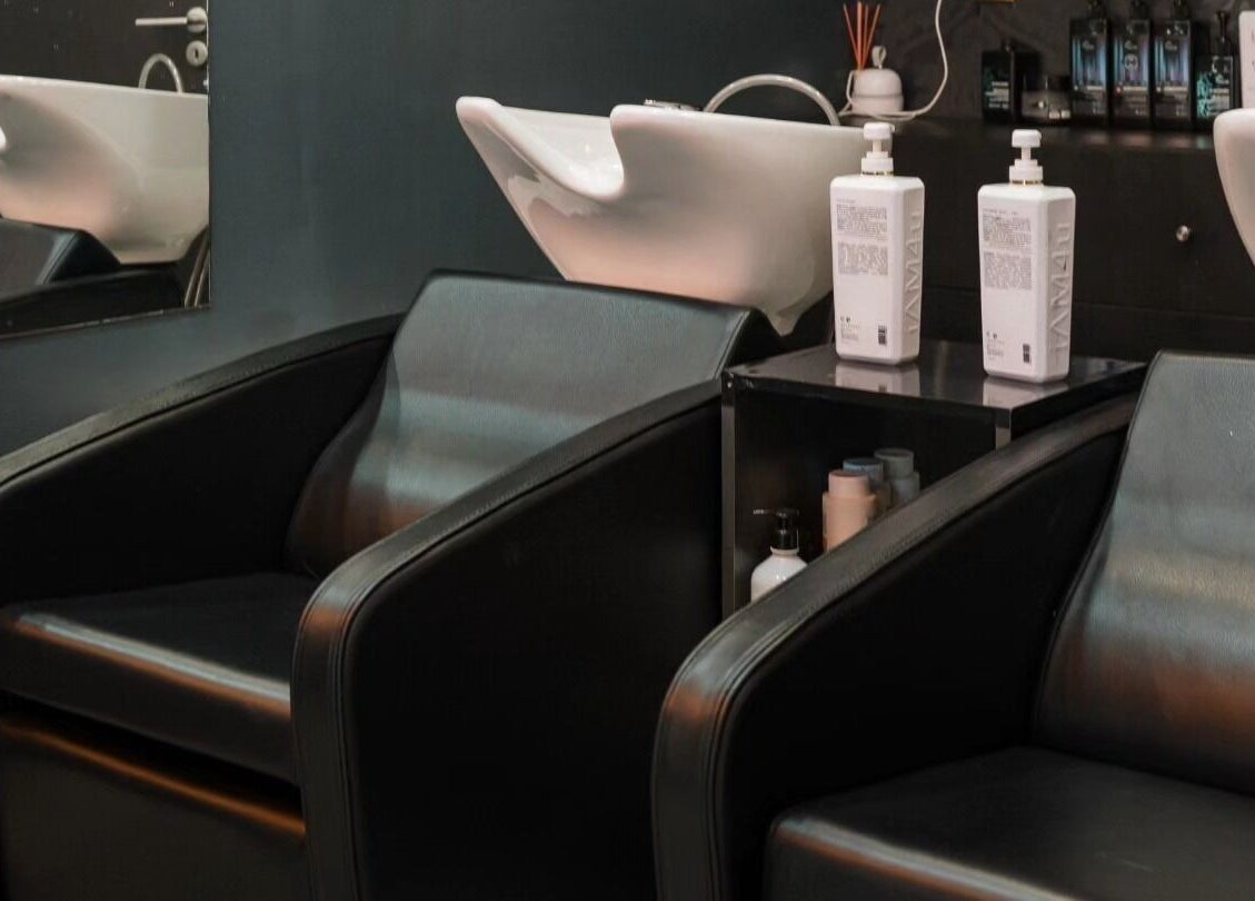 Área de lavagem moderna do Brauliun, Viseu, Viseu, PT, com poltronas pretas elegantes e produtos de beleza.