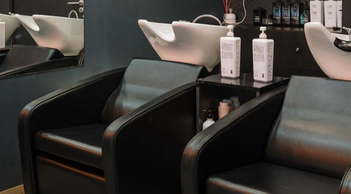 Área de lavagem moderna do Brauliun, Viseu, Viseu, PT, com poltronas pretas elegantes e produtos de beleza.