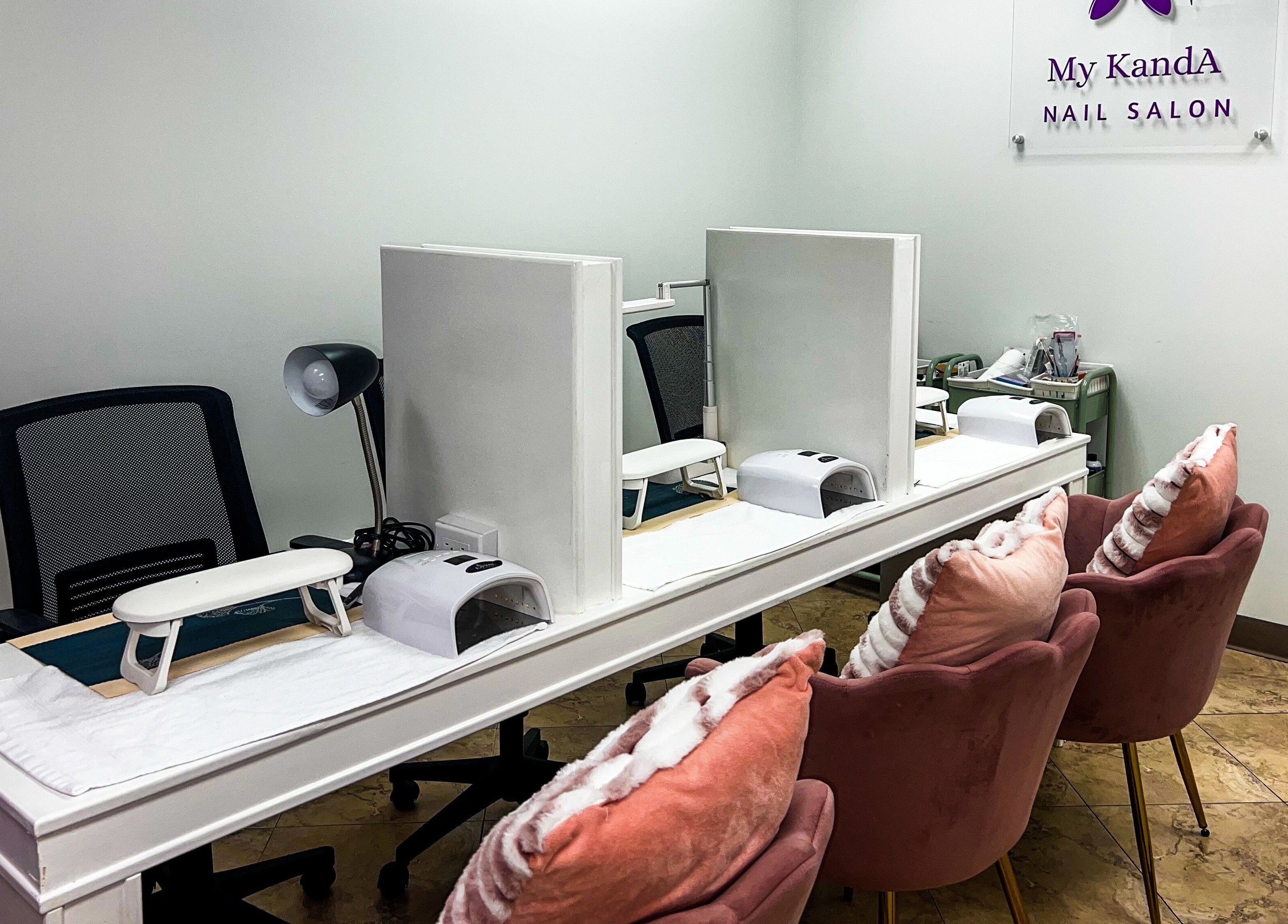 Chic nail stations at My KandA Nail Salon, Grand Cayman, showcasing stylish decor and plush chairs.