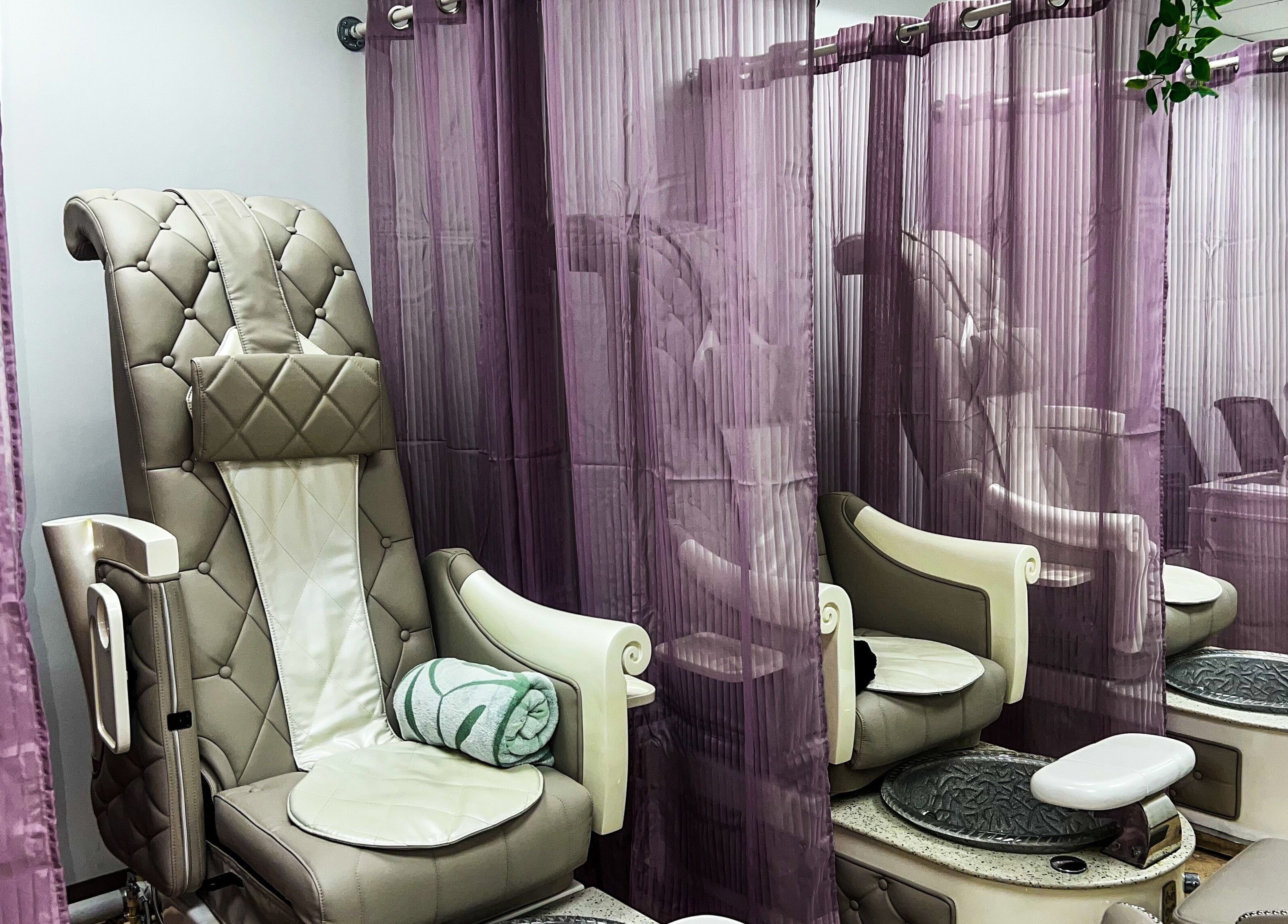 Luxurious pedicure chairs at My KandA Nail Salon, Grand Cayman, KY, adorned with purple curtains for privacy.