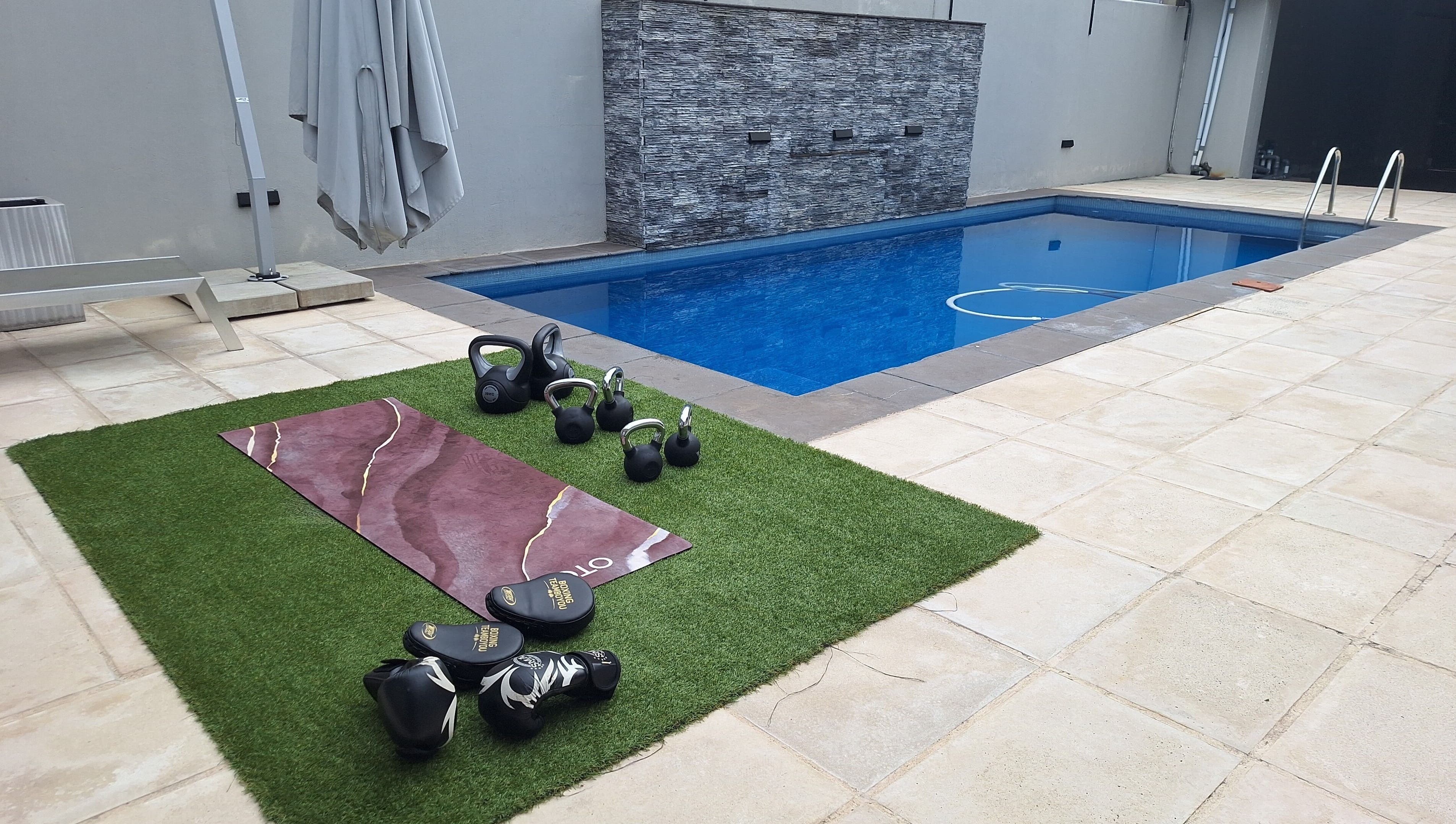 Outdoor workout setup at JK Personal Trainer in Cape Town, Western Cape, ZA with kettlebells by the pool.
