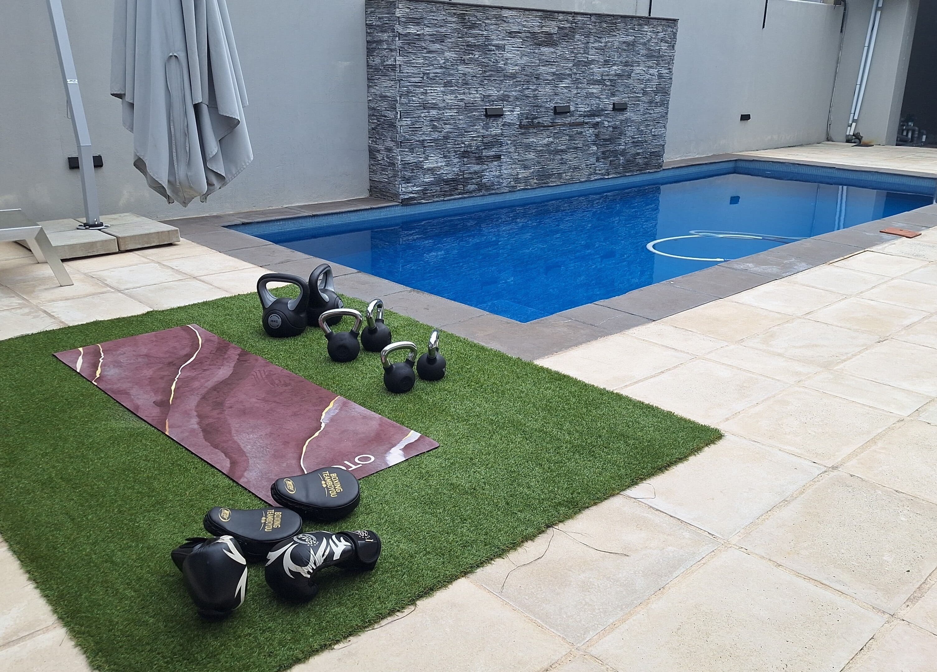 Outdoor workout setup at JK Personal Trainer in Cape Town, Western Cape, ZA with kettlebells by the pool.
