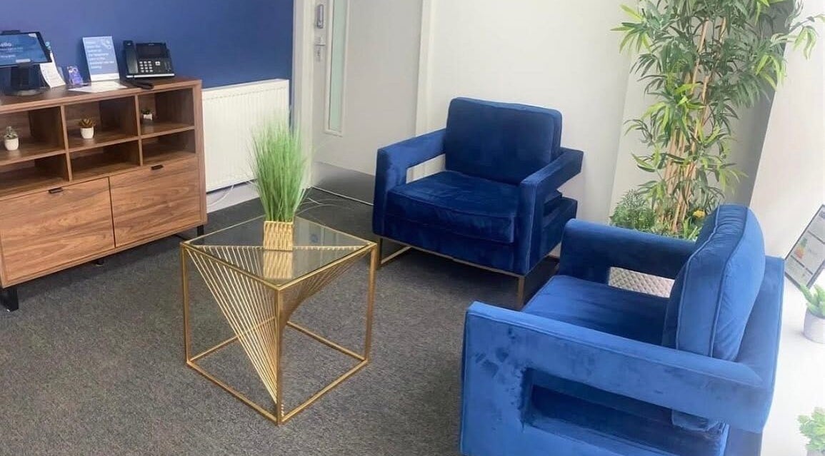 Cozy reception area at DB Skin/Therapy, Cleator Moor, England, GB with blue chairs and a modern table.