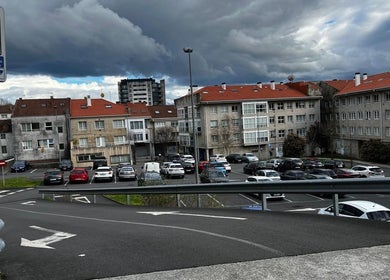 Vista urbana cerca de Beganur Massages en Santiago De Compostela, ES, mostrando edificios residenciales y estacionamiento.