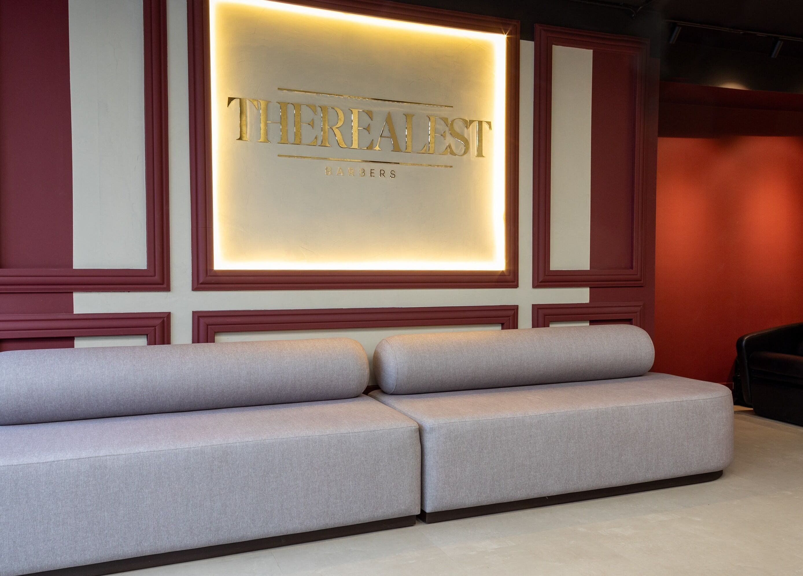 Stijlvolle wachtkamer bij The Realest Barbers Utrecht, Utrecht, NL met moderne bank en zachte verlichting.