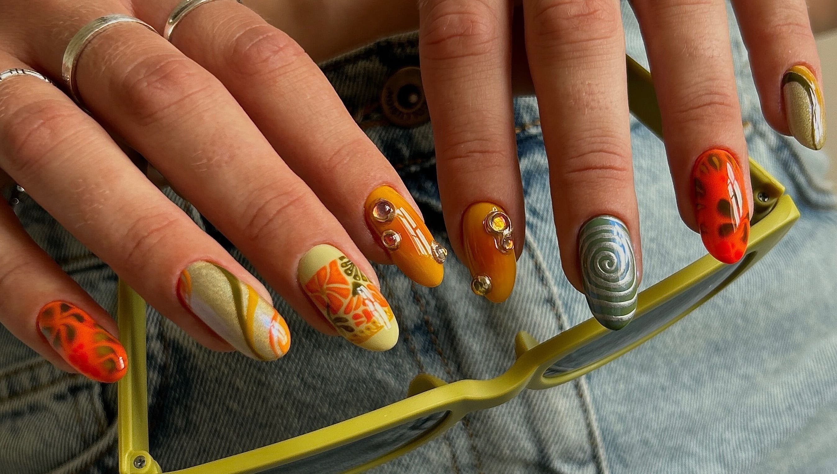 Colorful artistic nails at Phresh, Woodbridge, England, GB showcasing creative designs and gemstones.