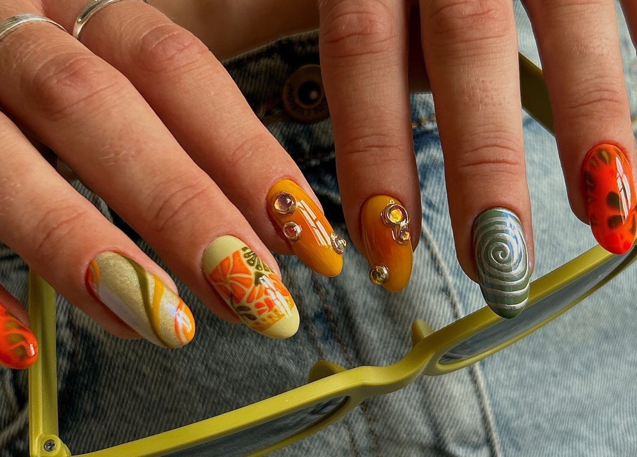 Colorful artistic nails at Phresh, Woodbridge, England, GB showcasing creative designs and gemstones.