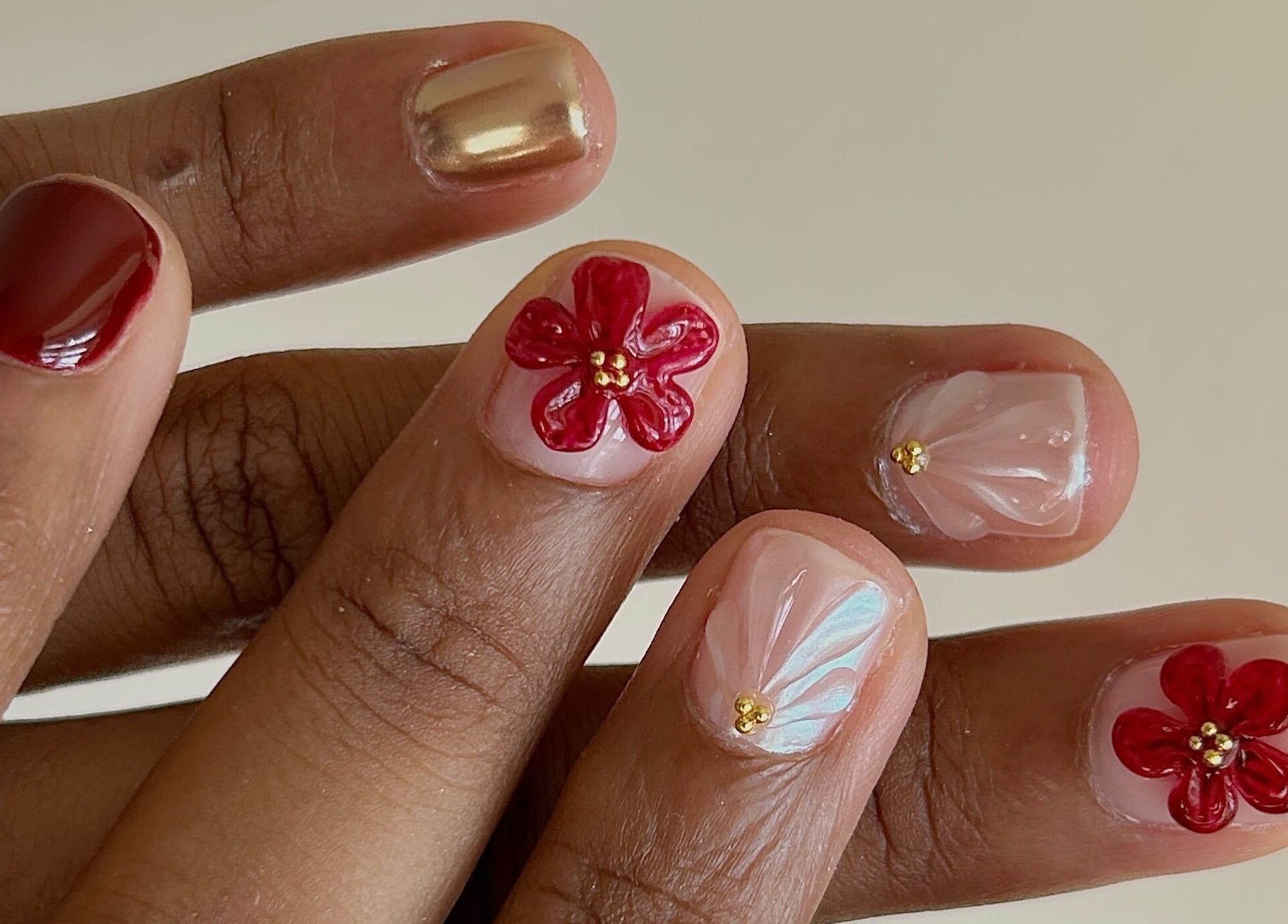 Elegant floral nail art at Phresh, Woodbridge, England, GB with red and gold accents.