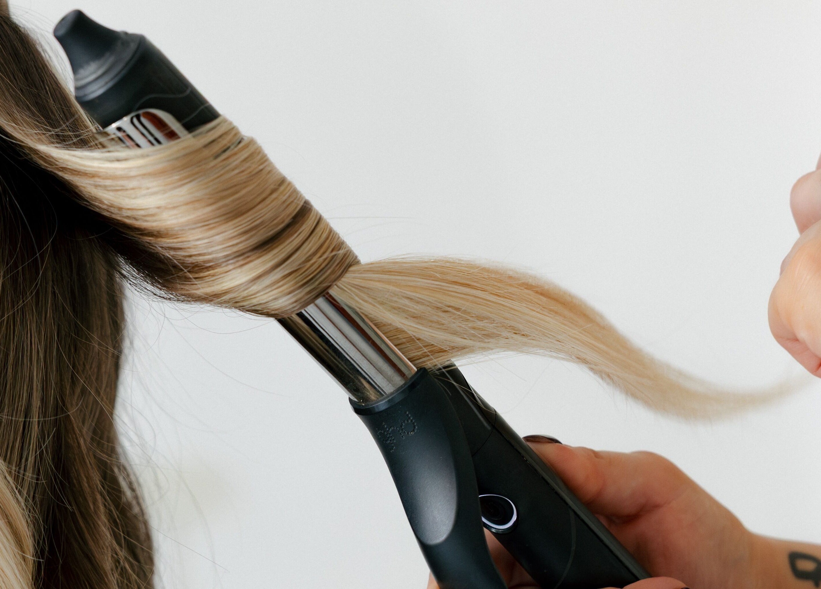 Styling blonde hair with a curling iron at Hair.ByTayah in Berkeley Vale, New South Wales, AU.