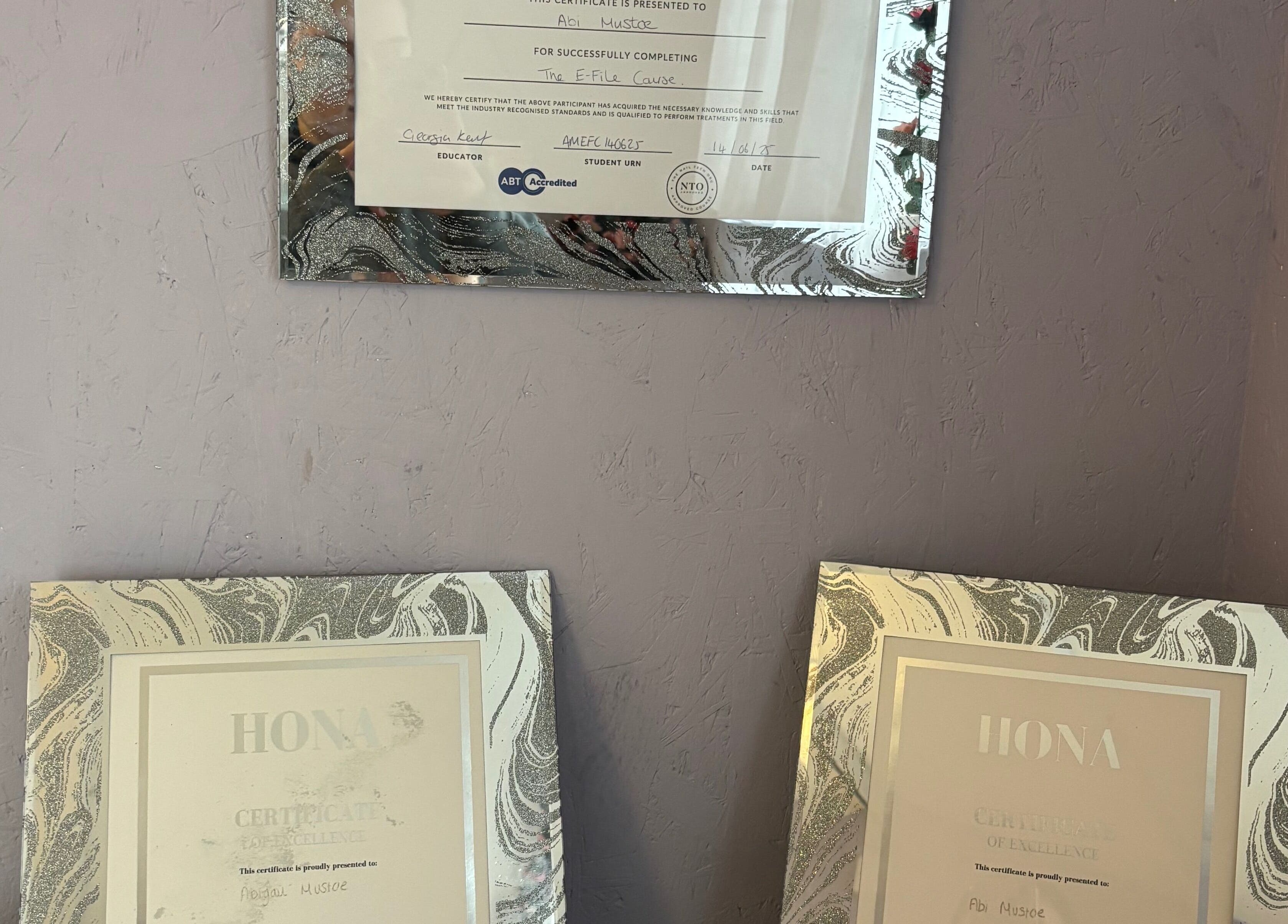 Certificates of excellence displayed at Next Level Nails, Northleach, England, GB showcasing professional achievements.