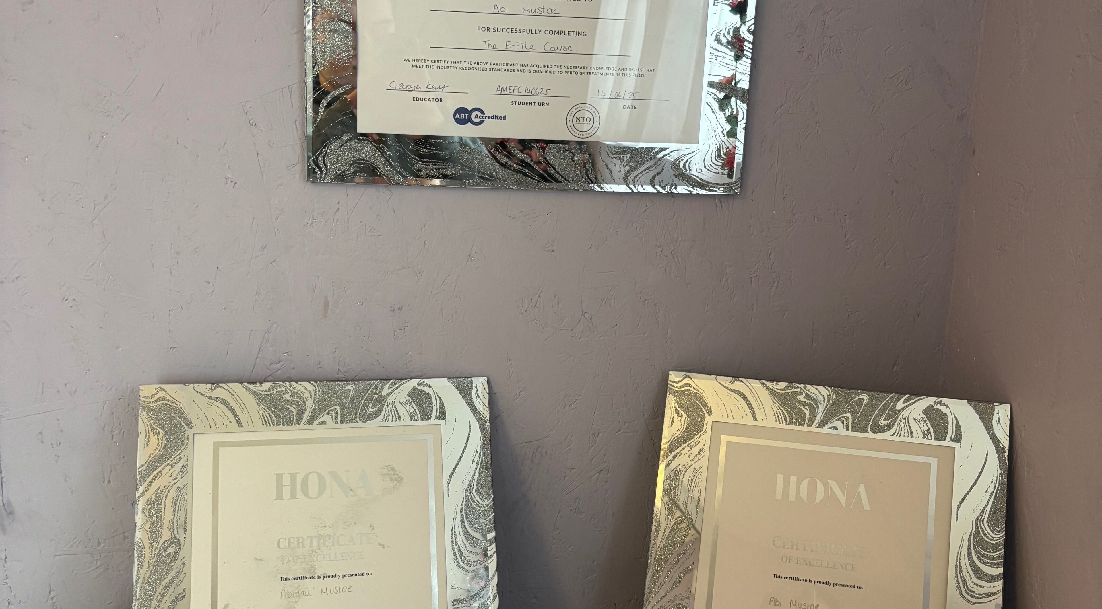Certificates of excellence displayed at Next Level Nails, Northleach, England, GB showcasing professional achievements.