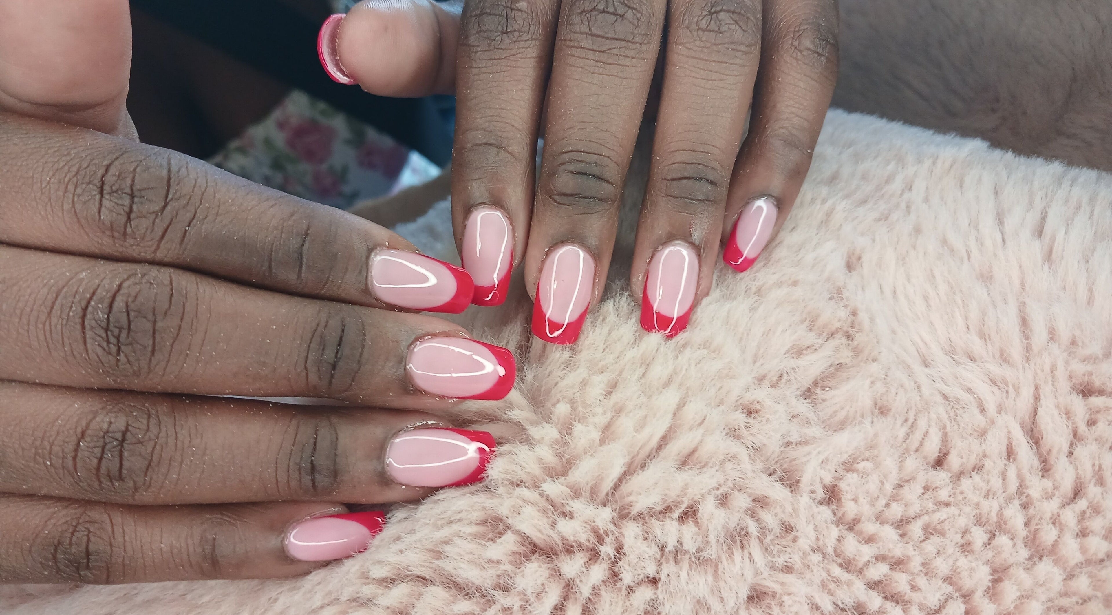 Red-tipped manicured nails from X Nails and Beauty, Ballito, Kwazulu-natal, ZA on a soft surface.